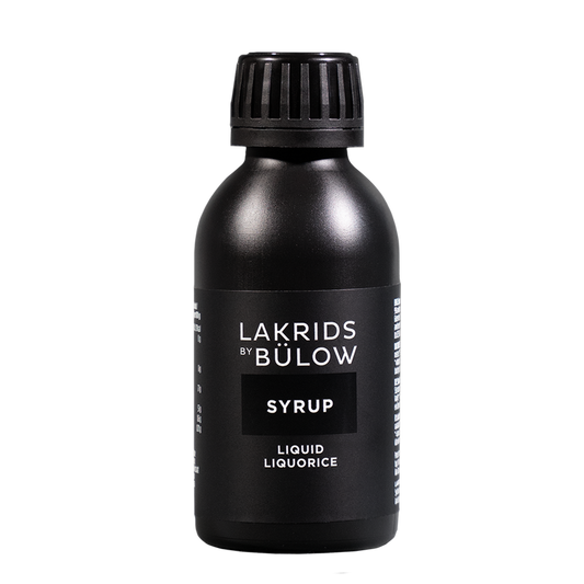 A matte black bottle of Lakrids by Bülow Syrup liquid liquorice, featuring a ribbed black cap and a minimalist black label with white text, set against a plain white background.